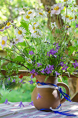 Image showing Jug with a bouquet of summer flowers on a table in the garden