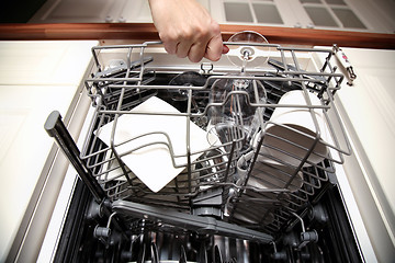 Image showing Woman\'s hand opening dishwasher with clean utensils