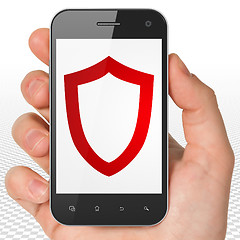 Image showing Safety concept: Hand Holding Smartphone with Contoured Shield on display