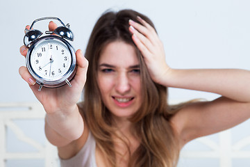 Image showing The young girl in bed with  clock service