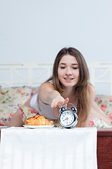 Image showing The young girl in bed with  clock service