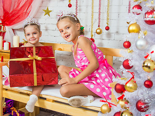 Image showing The girl gave a big red Christmas gift to his sister and looked into the frame
