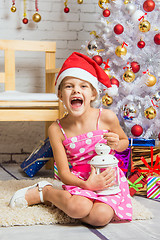 Image showing Girl screams happily holding candle in her hands and sitting by Christmas trees