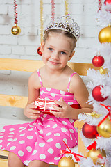 Image showing Four-year girl sitting on a bench at a snowy Christmas trees