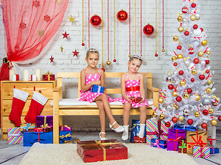 Image showing Happy sister holding gifts in their hands, and sit on a bench in a Christmas setting