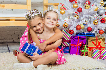 Image showing Girl hugging another girl sitting on a mat at the Christmas tree