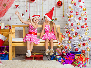 Image showing Two funny girls fool around sitting on a bench in a Christmas setting