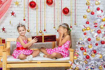 Image showing Girl gives another girl a gift sitting on a bench in a Christmas setting