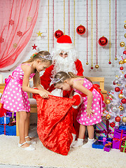 Image showing Girls looking at a gift bag with gifts that brought Santa Claus