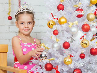 Image showing Girl hangs balls on a snowy New Years Christmas tree