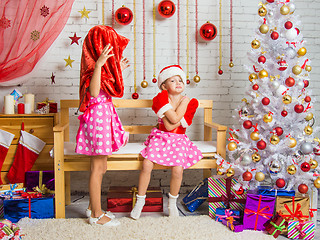 Image showing Girl wearing Santa Claus bag on his head, the other girl was offended sitting on the bench