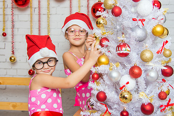 Image showing Two funny girls hanging balls on the Christmas tree