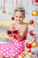 Image showing Four-year girl stretches forward a little gift sitting snowy Christmas trees