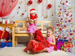 Image showing Girl in a cap and mittens of Santa Claus saw that bag climbs another girl