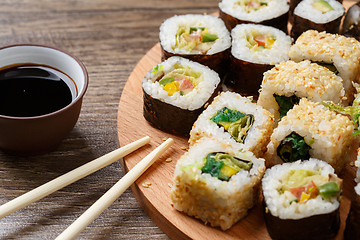 Image showing Sushi rolls with salmon and hot tea ceremony on black wooden table