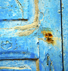 Image showing dirty stripped paint in the blue wood door and rusty nail