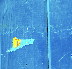 Image showing stripped paint in the blue wood door and rusty nail