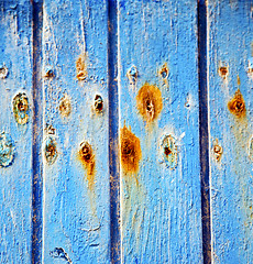 Image showing dirty stripped paint in the blue wood door and rusty nail