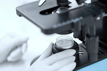 Image showing close up of hand with microscope and powder sample