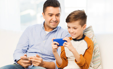 Image showing happy father and son with smartphone at home