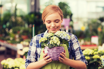 Image showing happy woman smelling flowers in greenhouse