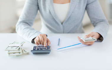 Image showing close up of hands counting money with calculator