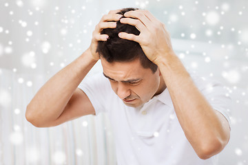 Image showing unhappy man suffering from head ache at home