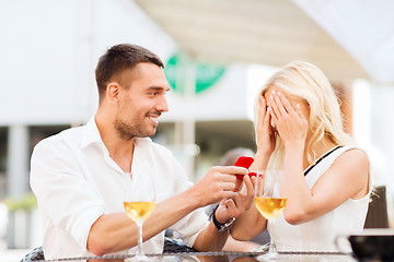 Image showing happy couple with engagement ring and wine at cafe
