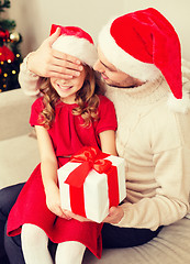 Image showing smiling father surprises daughter with gift box