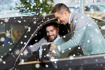 Image showing happy couple with car dealer in auto show or salon