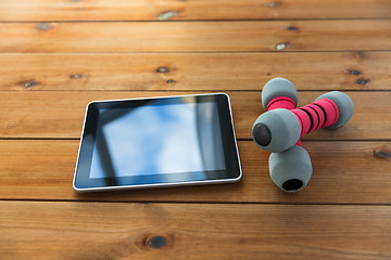 Image showing close up of dumbbells and tablet pc on wood