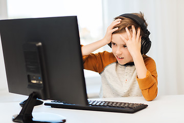 Image showing terrified boy with computer and headphones at home