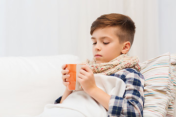 Image showing ill boy with flu in scarf drinking tea at home