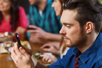 Image showing man with smartphone and friends at restaurant