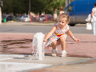 Image showing  The child touched his hand to the jet fountain gushing from the earth