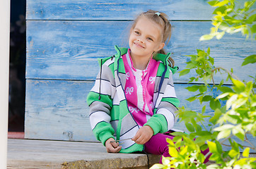 Image showing Happy girl sitting on the porch in the village