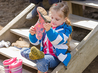 Image showing Girl wears boots sitting on the porch in the village