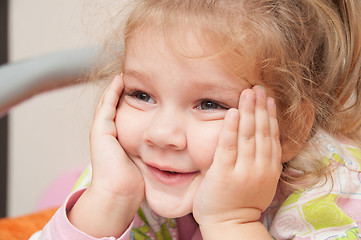 Image showing The three-year girl interested looking at the left hand propping cheek