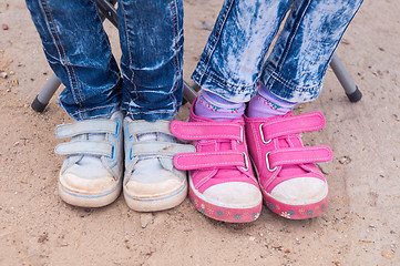 Image showing Close-up of two pairs of children\'s feet dressed in jeans and sneakers