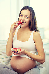 Image showing happy pregnant woman eating fruits at home