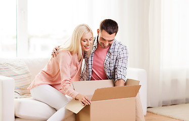 Image showing happy couple with cardboard box or parcel at home