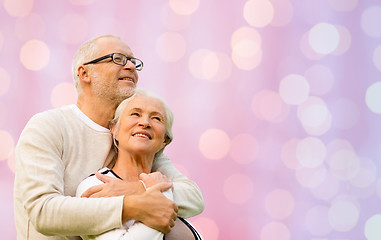 Image showing happy senior couple hugging over lights background