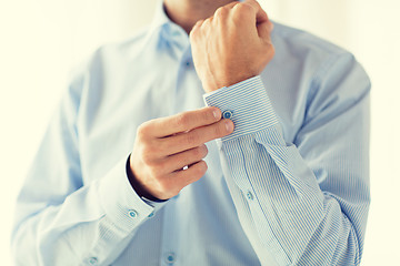 Image showing close up of man fastening buttons on shirt sleeve