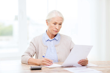 Image showing senior woman with papers and calculator at home