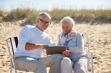 Image showing happy senior couple with tablet pc on summer beach