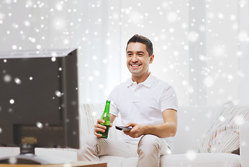 Image showing smiling man watching tv and drinking beer at home