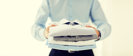 Image showing close up of businessman holding folded shirts