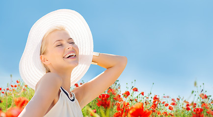 Image showing smiling young woman in straw hat on poppy field