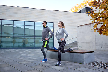 Image showing happy man and woman exercising on bench outdoors