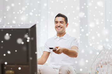 Image showing smiling man with remote control watching tv